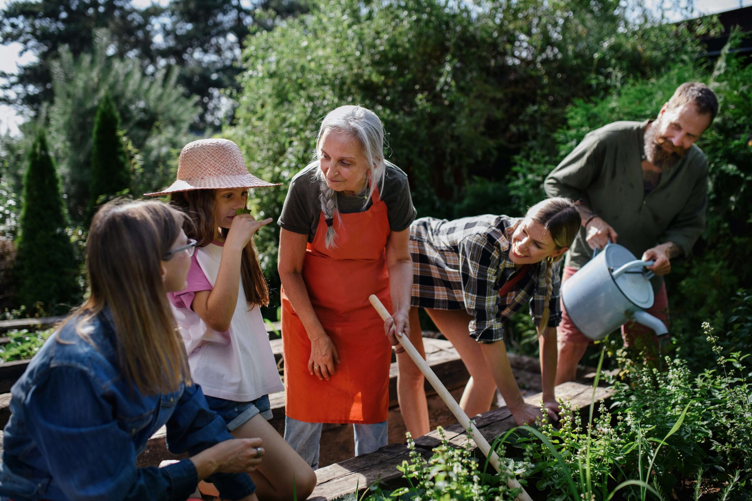 Older woman mentoring a group of young people in a community garden, representing MitoKhon's Social Impact Strategy and Advising initiatives for positive community outcomes.